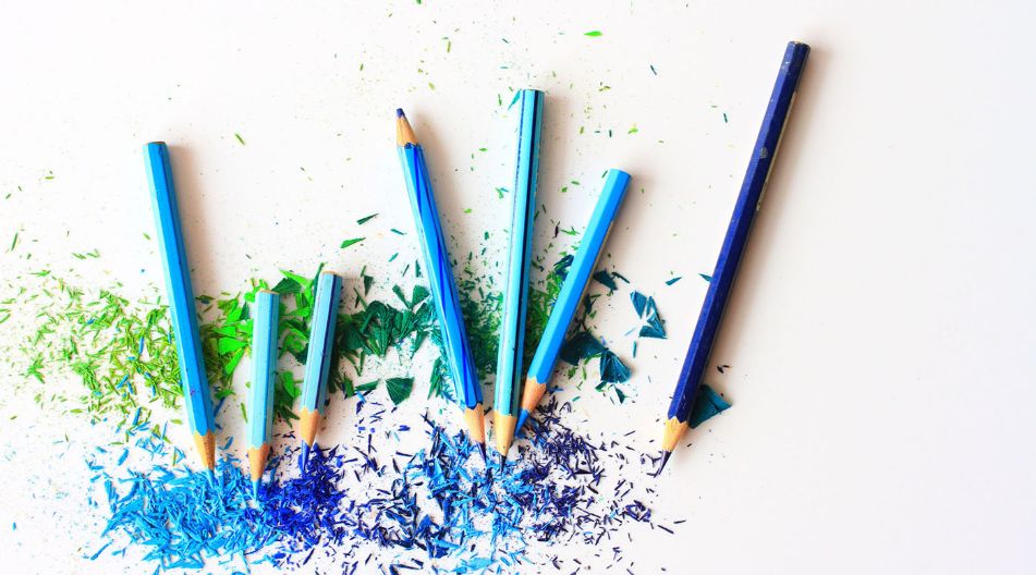 Buntstifte in verschiedenen Blautönen liegen auf einer weißen Oberfläche, einige sind angespitzt und unterschiedlich lang. Farbige Späne in Blau und Grün sind um die Stifte herum verstreut. Buntstifte in verschiedenen Blautönen liegen auf einer weißen Oberfläche, einige sind angespitzt und unterschiedlich lang. Farbige Späne in Blau und Grün sind um die Stifte herum verstreut.