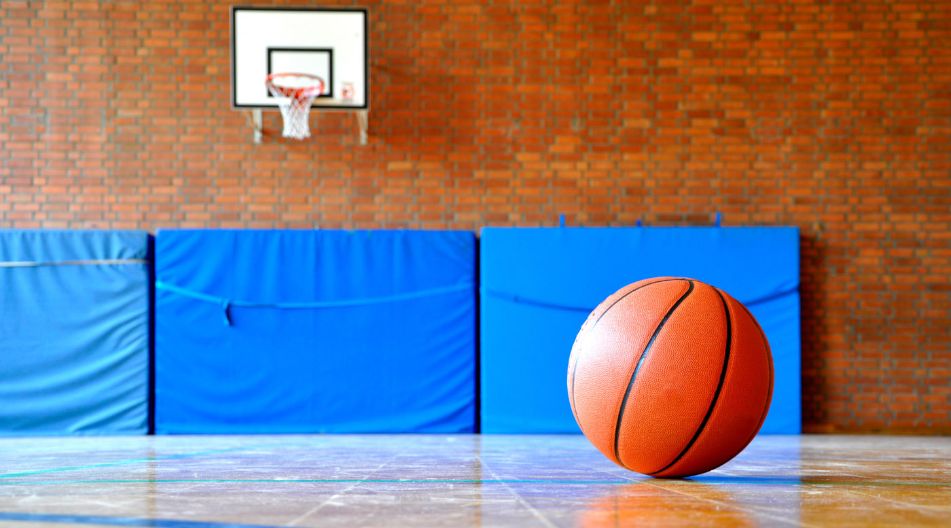 Ein Basketball liegt allein in einer Sporthalle. An der Wand sind Weichbodenmatten zu sehen. Ein Basketball liegt allein in einer Sporthalle. An der Wand sind Weichbodenmatten zu sehen.